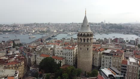 Vista-Aérea-De-La-Torre-De-Gálata-En-Beyoglu-Estambul-Con-El-Mar-Del-Bósforo,-Mezquitas-Y-El-Puente-De-Gálata-Al-Fondo-Detrás