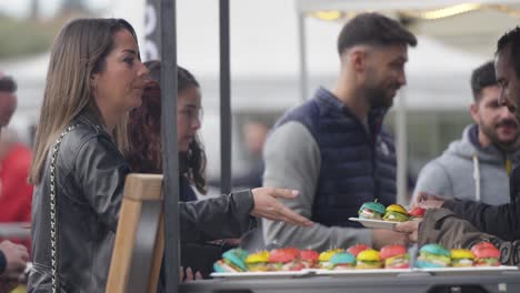 woman buying colorful mini burgers at outdoor food market