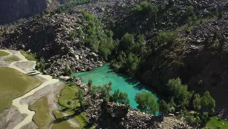 cinematic drone shot of turquoise colored water in the mountains at naltar valley in pakistan, slow descending towards lake, aerial shot