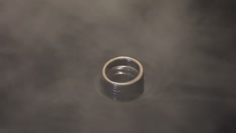 wedding rings on dark water surface shining with light. close up macro