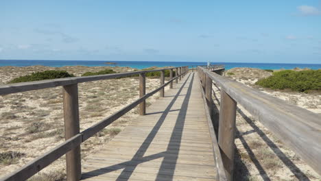 man tourist walking alone at the end of a long wooden bridge that goes towards the sea, sunny day