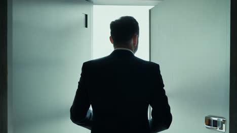 man in suit walks through an open door