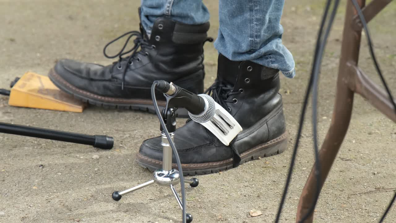A performance by a musician playing the tambourine on his foot while stamping to keep the beat to the song.