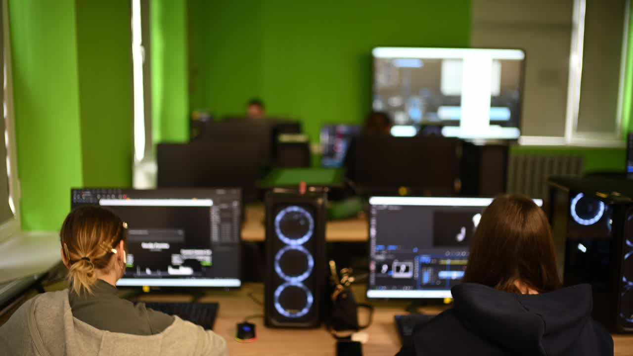 Modern computer classroom with multiple workstations, screens and students working