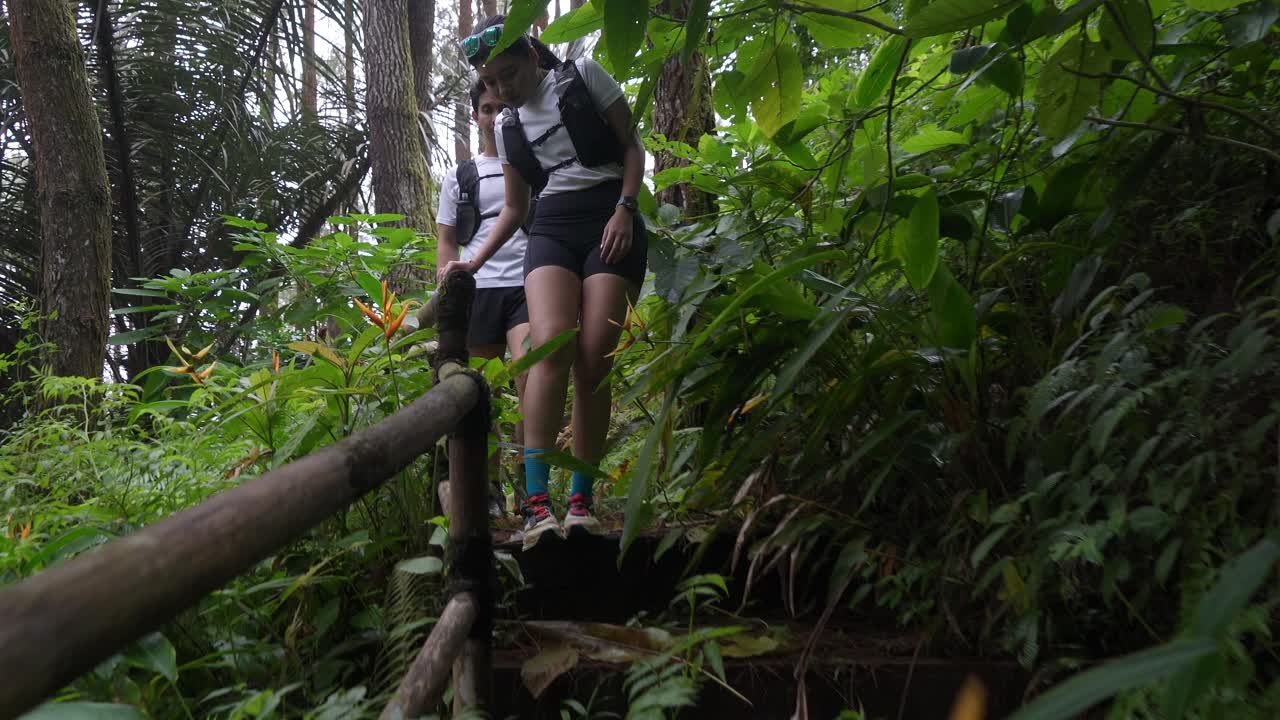 Asian couple walking on forest trail path during outdoor adventure in Indonesia