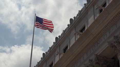 american flag rising above an old building in manhattan