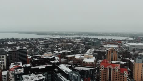 aerial-of-downtown-Madison,-Wisconsin-in-the-winter,-snow-capped-rooflines-and-Lake-Mendota-in-the-distance