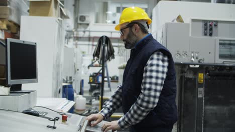 side view of concentrated male worker setting printing machine