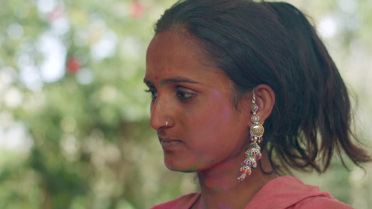 인도 여성의 가까운 얼굴은 밝은 홀리 색으로 얼룩져 있습니다.