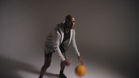 toma de estudio de un jugador de baloncesto masculino dribbling y lanzando la pelota contra un fondo oscuro