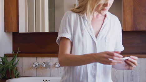 Excited-Woman-Looking-At-Positive-Result-Pregnancy-Test-In-Bathroom