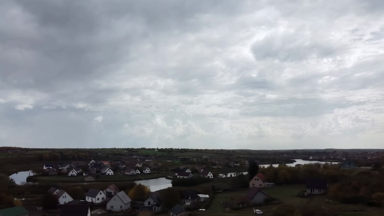 Overcast Village Skyline Cinematic Drone Shot Capturing Dramatic Low Clouds, Quiet Rooftops, River
