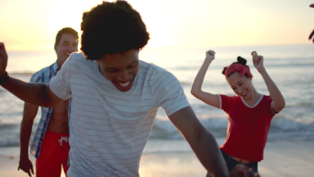 Diverse young friends enjoy a playful moment on the beach at sunset