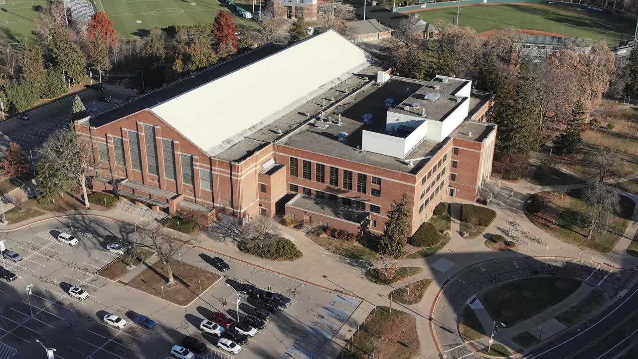 Cinematic rotating aerial shot around Jenison Fieldhouse at Michigan State University capturing the historic architecture and expansive campus grounds