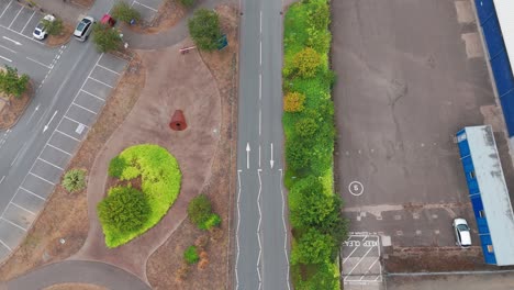 an aerial view of a roundabout with distinct lane markings and curbside parking. the scene includes buildings, sidewalks, and vegetation, showcasing urban planning