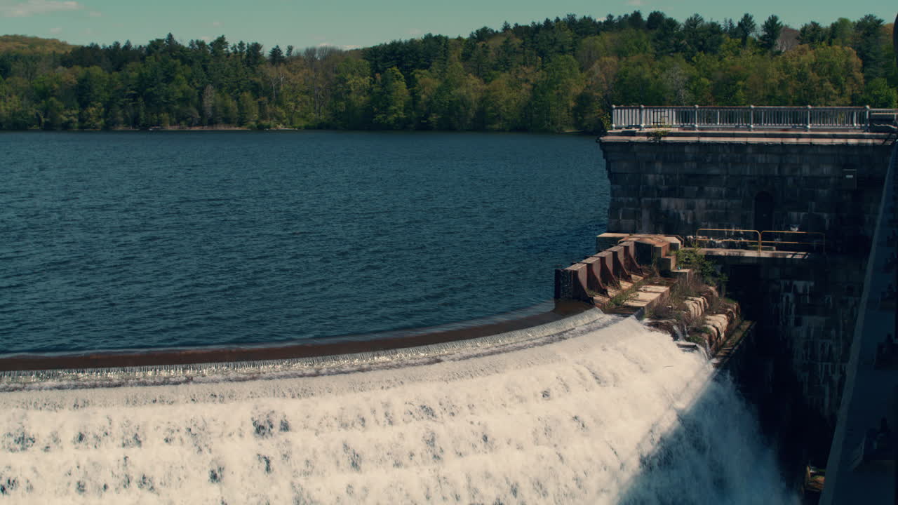 medium shot of new croton reservoir stepped spillway with lake, mountains and blue sky in the background. slow motion 40fps