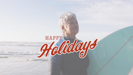 happy holidays text over person holding surfboard on beach