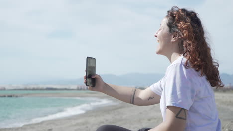 young woman with phone on beach