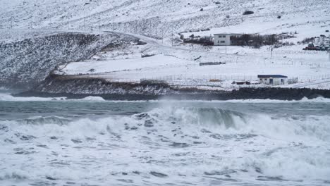 slow motion: waves of arctic ocean reaching beach at ólafsfjörður town in north iceland during snowy winter day