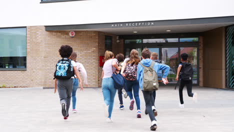 group of high school students running into school building at beginning of class