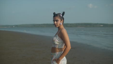 beautiful and wild woman looks at the camera doing concentration pose on the indian beach