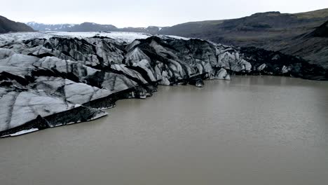 drone flying on the edge of glacier in iceland with glacial lake