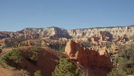 Handheld-shot-of-a-stunning-orange-and-green-desert-landscape-in-Southern-Utah-with-hoodoo-and-other-sandstone-formations-due-to-erosion-surrounded-by-greenery-on-a-bright-summer-morning