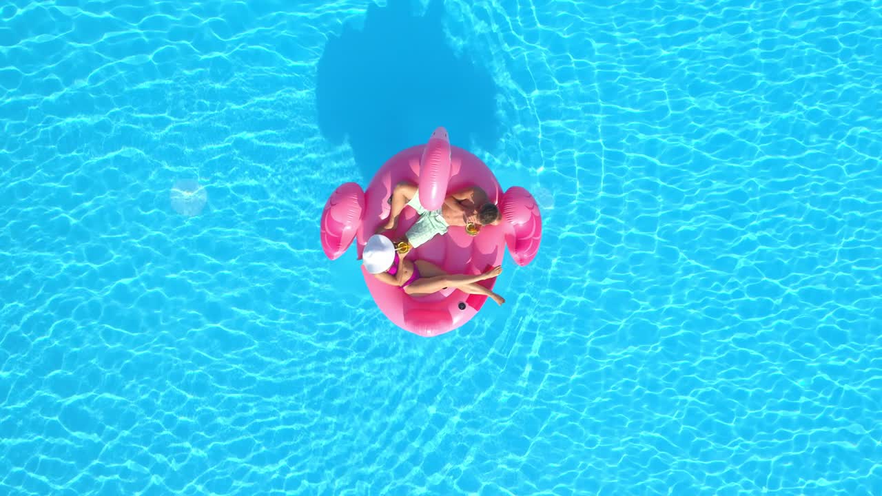 DRONE Man and his girlfriend on summer vacation chill on a pink flamingo floatie