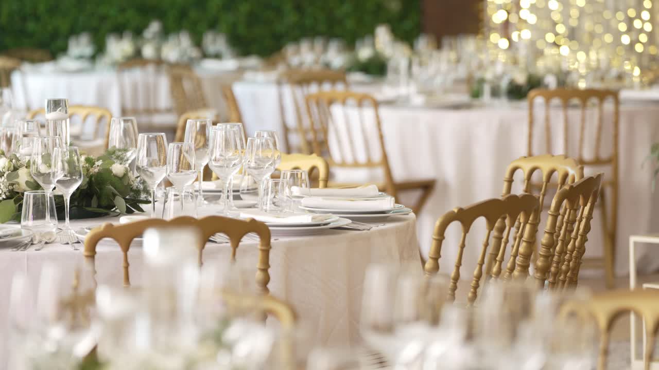 Luxurious wedding table setting with golden chairs, glassware, and floral centerpieces
