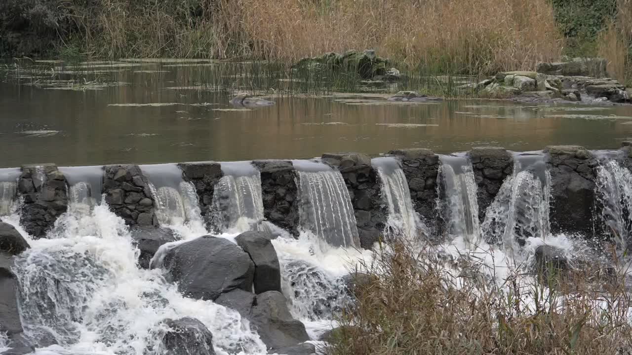 강물이 돌 위어 위로 분출하고 슬로우 모션