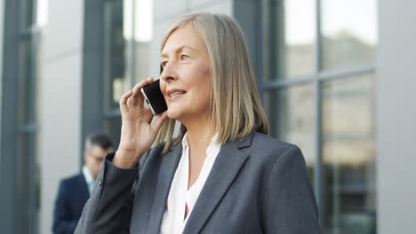 close up view of mature businesswoman talking on the phone in the street