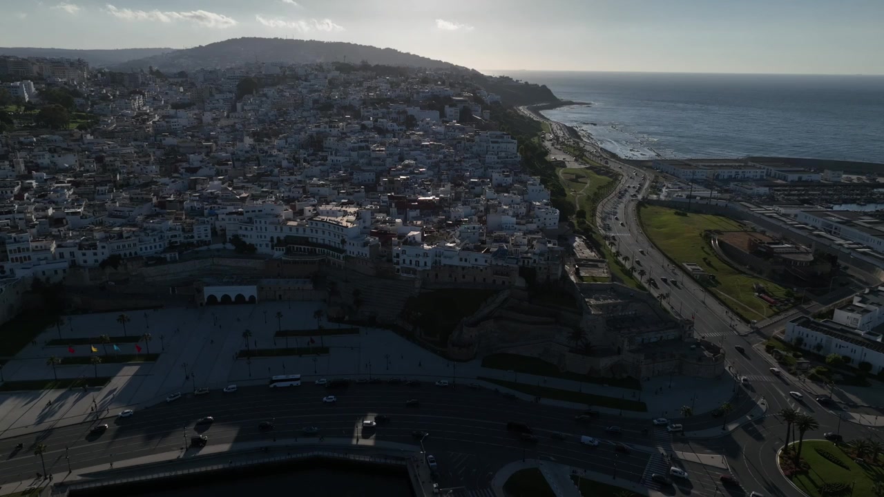 Vista aérea de una densa ciudad histórica descendiendo hacia el mar Mediterráneo, con murallas fortificadas, una gran plaza urbana y barrios en la ladera en el norte de Marruecos.