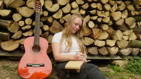 female guitarist songwriter composes chords and lyrics by rustic logs