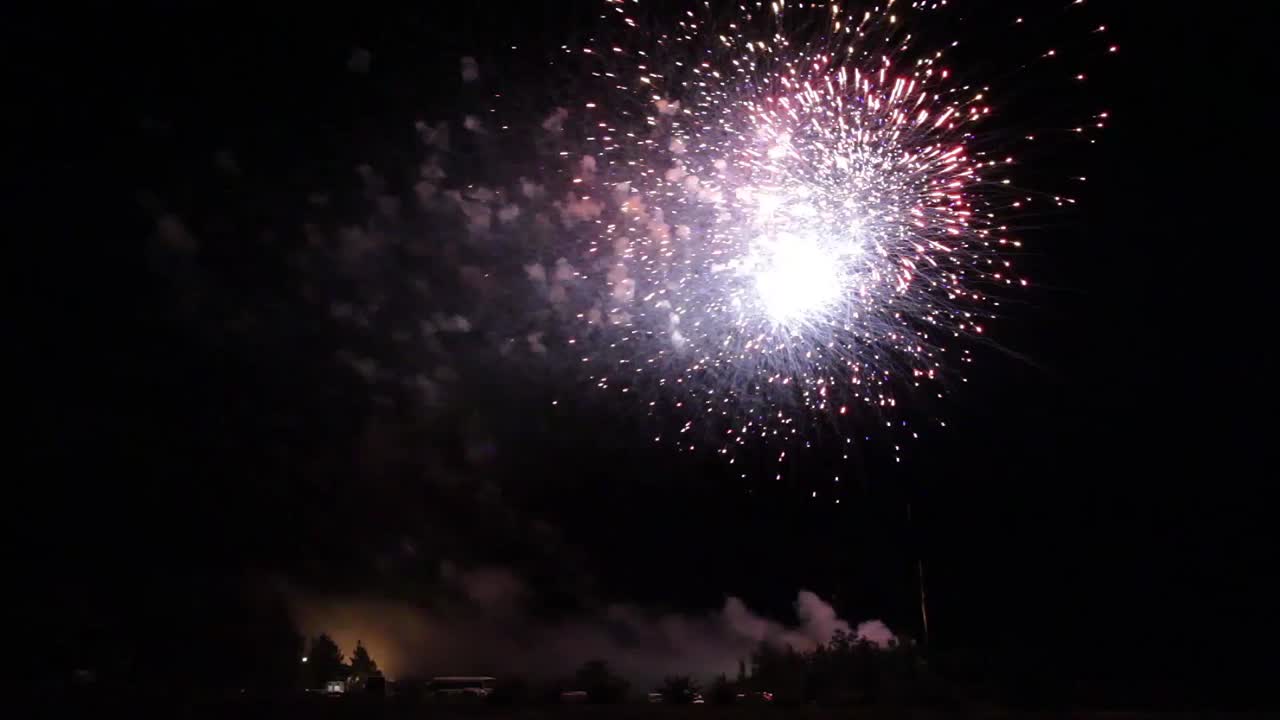 Big fireworks during a celebration in the middle of the countryside. Night sky illuminated by the fireworks and the smoke