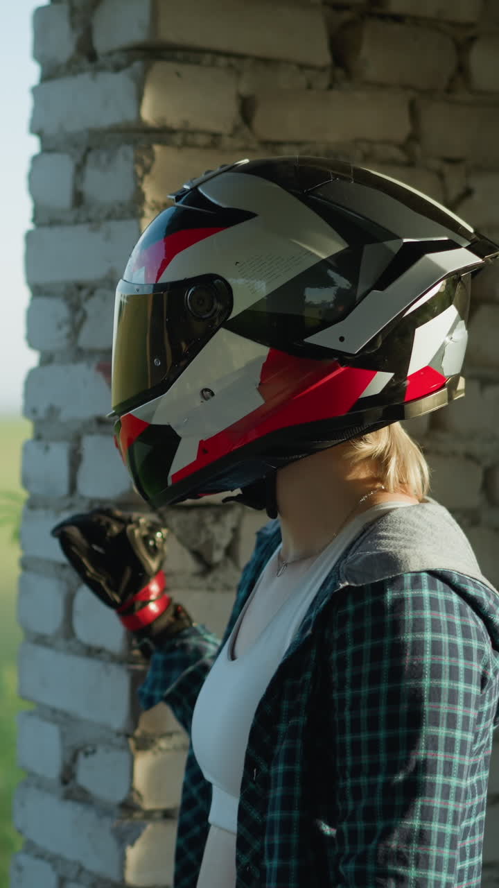 dos mujeres con cascos de pie dentro de un edificio abandonado, una colocando su mano en la pared mientras mira afuera a la vegetación