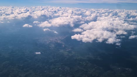 flying above clouds and landscape of belize countryside, airplane passenger pov