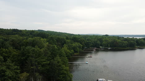 Aerial-parallax-around-forested-lake-side-docks-on-cloudy-day