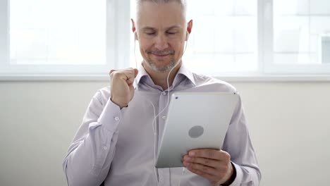 hombre de mediana edad escuchando música en la tableta y bailando
