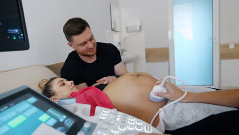 caucasian couple is in the doctor's cabinet. pregnant woman has ultrasound check up.