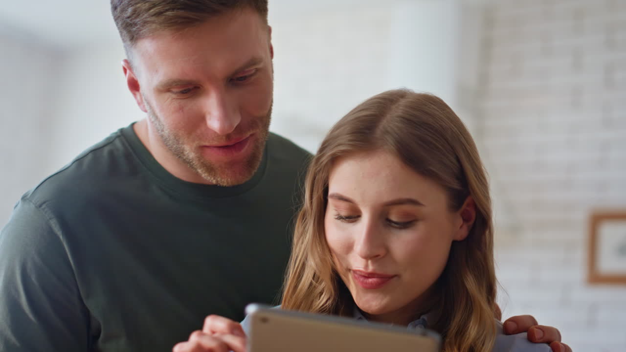 Morning lovers looking tablet in apartment kitchen closeup. Couple reading pad