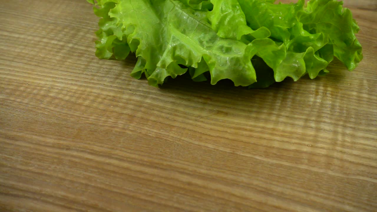 Hojas de lechuga cayendo sobre una tabla. Cámara lenta