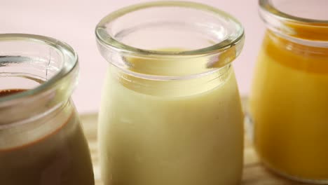 caramel, chocolate and mango pudding in a glass jar on pink background ,