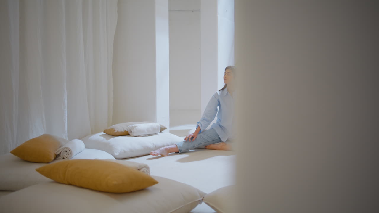 мечтательная женщина отдыхает в одиночестве в уютном пространстве для йоги.