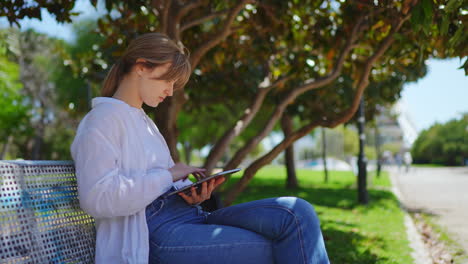 young woman relaxing in park with tablet