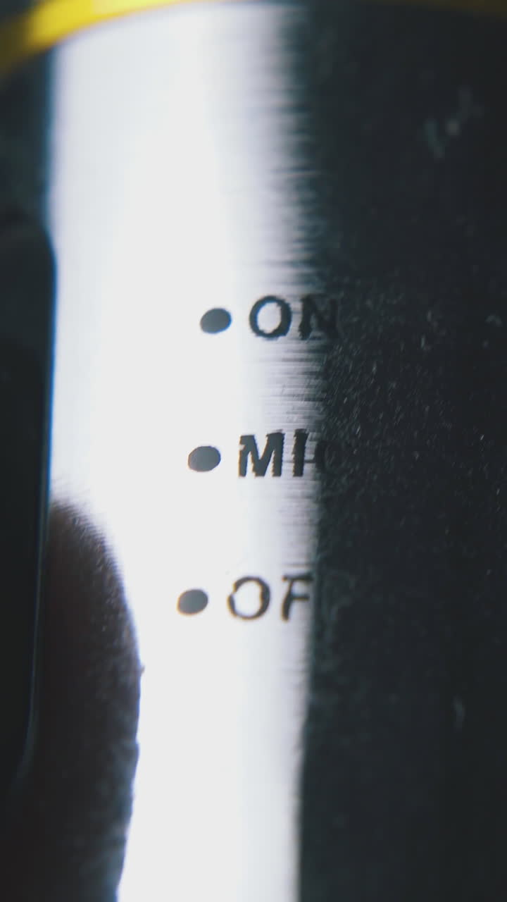 speaker switches on modern shining metallic microphone by finger on dark background extreme close view