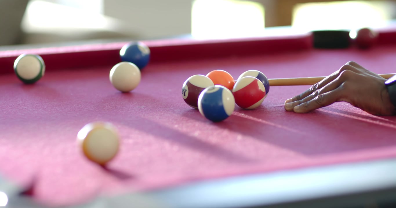 Man aiming, bridging and striking cue ball on red felt table to scatter balls, copy space