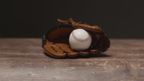 close up studio baseball still life with ball in catchers mitt on wooden floor