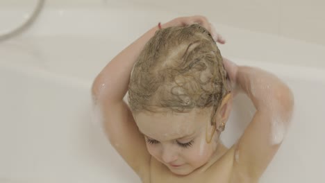 attractive three years old girl takes a bath. cleaning and washing hair