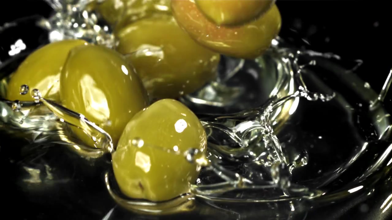 Olive che cadono e schizzano in un liquido al rallentatore
