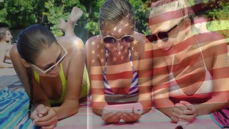 animation of flag of usa over happy caucasian female friends having fun at swimming pool